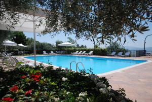 Hotel La Terrazza RESTAURANT & SPA في أسيسي: مسبح فيه كراسي ومظلات وزهور