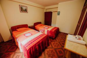 Habitación con 2 camas y mesa. en Hotel Las Viñas, en Huánuco