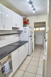 a kitchen with white cabinets and a white refrigerator at Bayview Beach Holiday Apartments in Gold Coast