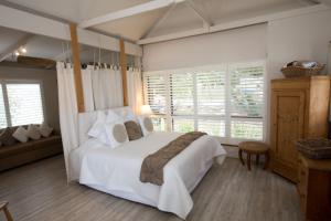 a bedroom with a large white bed and windows at Boathouse - Birks River Retreat in Goolwa