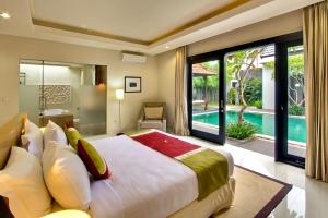 1 dormitorio con 1 cama grande y piscina en The Nibbana Villas, en Seminyak