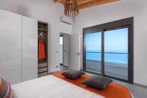 1 dormitorio con 1 cama y vistas al mar en Kathisma Bay Villas - Luxury Villas- Villa Oceanos, en Kalamitsi