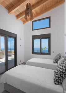 1 dormitorio con 2 camas y ventana en Kathisma Bay Villas - Luxury Villas- Villa Oceanos, en Kalamitsi