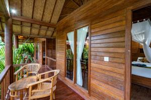 Casa de madera con porche con mesa y sillas en Dream Beach Inn, en Nusa Lembongan