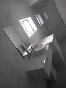 a white bathroom with a sink and a mirror at Kindred Parkside Apartments in Leeton