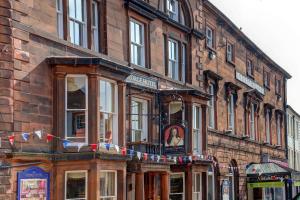 um grande edifício de tijolos com uma placa em The George Hotel em Penrith