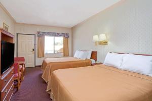 a hotel room with two beds and a flat screen tv at Travelodge by Wyndham Lynwood in Lynwood