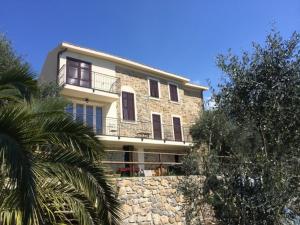a building on a stone wall with a palm tree at Agriturismo Osteria du Barba Pe' - Casa Cassini in Bordighera