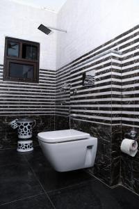 a bathroom with a toilet and a black and white wall at Hotel Amar Leela in Dehradun