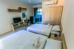 a hotel room with two beds and a television at Tempo Plus Apartment in Mae Sot