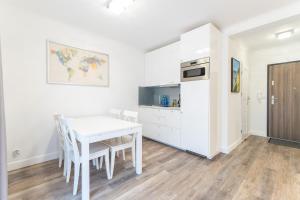 a white dining room with a white table and chairs at Kolorowe Balkony III by Renters in Międzyzdroje