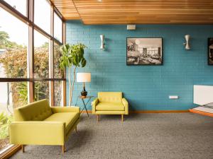 sala de estar con sillas amarillas y pared azul en Riverfront Motel & Villas, en Hobart