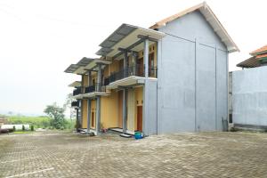 a building on a street next to a brick road at Villa Kangen Omah in Mojokerto
