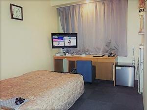a bedroom with a desk with a computer and a bed at Asano Hotel in Kitakyushu