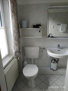 ein weißes Bad mit einem WC und einem Waschbecken in der Unterkunft Atlantis Landpension Steinhude in Wunstorf
