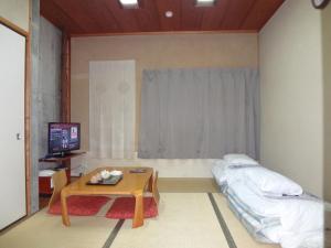 a room with a bed and a table and a television at Asano Hotel in Kitakyushu