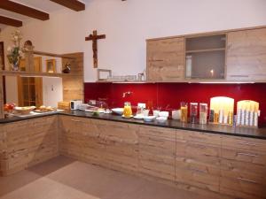 a kitchen with wooden cabinets and a cross on the wall at Pension Vocario in Pfarrwerfen