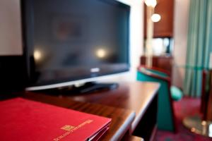 un livre rouge assis sur un bureau avec une télévision dans l'établissement Hotel Schloss Schwarzenfeld, à Schwarzenfeld