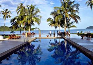 einen Pool am Strand mit Palmen und dem Meer in der Unterkunft Frangipani Langkawi Resort in Pantai Cenang