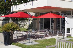 two red umbrellas and tables and chairs on a patio at Hôtel & Restaurant des Remparts in Rochefort