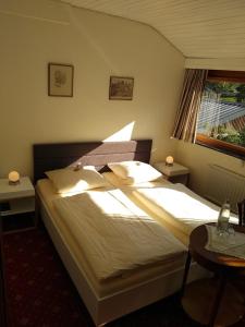 a bedroom with a bed with two tables and a window at Pension Auf der Olk mit Röpertsmühle in Veldenz