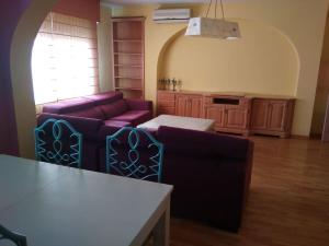 a living room with purple couches and a kitchen at Espacioso piso en el corazón de Oliva in Oliva