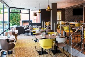 a dining room with tables and yellow chairs at Novotel Metz Amnéville in Maizières-lès-Metz