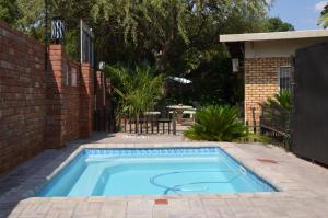 a swimming pool in a yard with a brick wall at Zebra Guesthouse in Lephalale