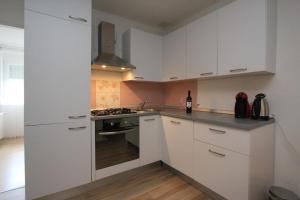 cocina con armarios blancos y fogones en Gospic Riverside Apartment, en Gospić