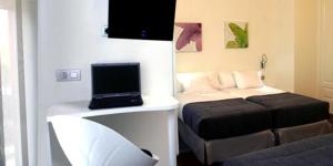 Habitación con cama y ordenador portátil en una mesa en Hostal Acuarela, en Burgos