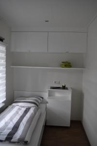 a white bedroom with a bed and a white cabinet at Ferienapartment am See in Wettringen