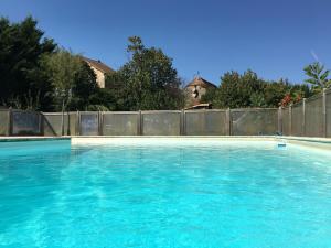 a large blue swimming pool with a fence at La Closerie des Arts in Gabillou