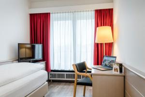 a room with a bed, desk, television and a lamp at Hotel IMLAUER & Bräu in Salzburg
