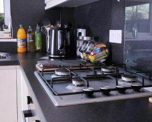 uma bancada de cozinha com uma placa de fogão numa cozinha em 6 berth, 3 dbl bed-2 sngl bed-sofabed-2 shwr-2WC-offroad van park-washer-dryer-Business WiFi em Corby