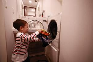 a young boy is loading a washing machine at Hotel Axas Nihonbashi in Tokyo