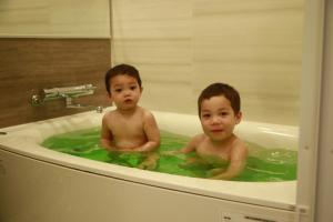 deux jeunes garçons assis dans une baignoire dans l'établissement Hotel Axas Nihonbashi, à Tokyo
