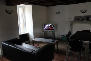 sala de estar con sofá, mesa y TV en Gite des Celliers en Alise-Sainte-Reine