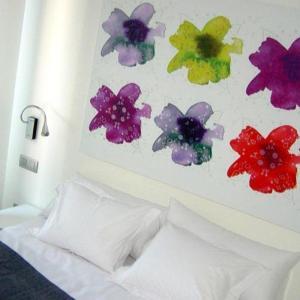 una pintura de flores en una pared sobre una cama en Hostal Acuarela, en Burgos