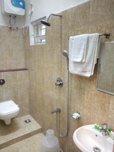 uma casa de banho com um chuveiro, um WC e um lavatório. em Medavakkam Sri Sai Residency em Chennai