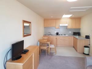 a kitchen with a desk with a television and a table at Fairways Cottages in Prestwick