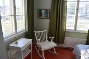 a bedroom with a rocking chair and a table and windows at Villa Björksten in Loviisa