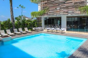 a swimming pool with chairs and a table on a building at The Double View Mansions Bali in Canggu