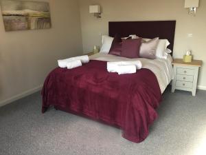 een slaapkamer met een groot bed met paarse lakens en kussens bij The Clifden Arms B&B in Worminghall