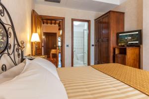 a bedroom with a bed and a television and a bathroom at Hotel Ristorante La Pergola in Magliano Sabina