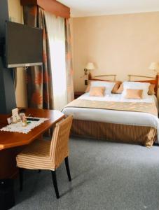 a hotel room with a bed and a desk with a desk at Le Haut Allier in Alleyras