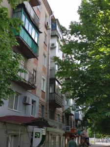 a tall building on a city street with trees at НЕ ВИМИКАЮТЬ СВІТЛО lark apartment in Dnipro