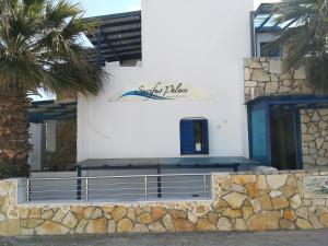 a white building with a palm tree in front of it at Serifos Palace in Livadakia