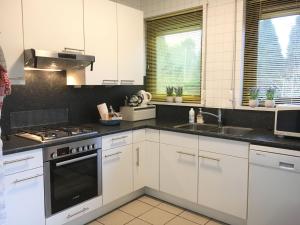 a kitchen with white cabinets and a stove top oven at Vakantiehuis Jacobo in Burgh Haamstede