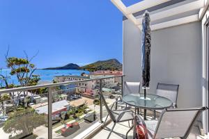 a balcony with a table and chairs and a view of the ocean at The Shoal Apartments, Unit 504/4-8 Bullecourt Street in Shoal Bay