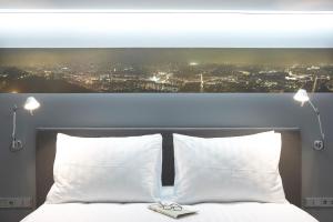 a bed with two white pillows and a picture of a city at Periscope in Athens